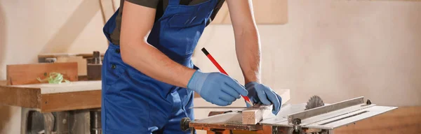 Professional carpenter making mark on wooden bar in workshop, closeup. Banner design