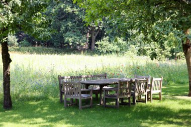 Empty wooden table with bench and chairs in garden
