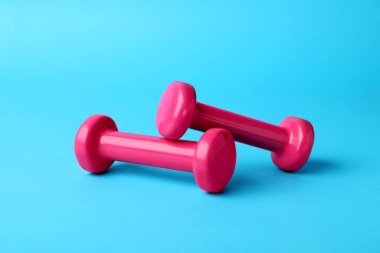 Two stylish dumbbells on light blue background