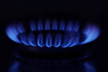 Karanlığın içinde yanan alevlerle gaz ocağı, yakın çekim