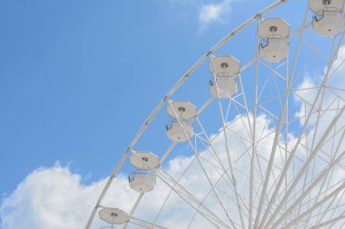 Mavi bulutlu gökyüzüne karşı geniş bir gözlem çarkı, alçak açı. Metin için boşluk