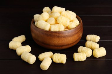 Koyu ahşap masada mısır çubukları olan bir kase.