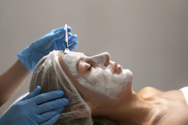 Spa salonu müşterinin yüzüne maske uygulayarak güzellik uzmanı