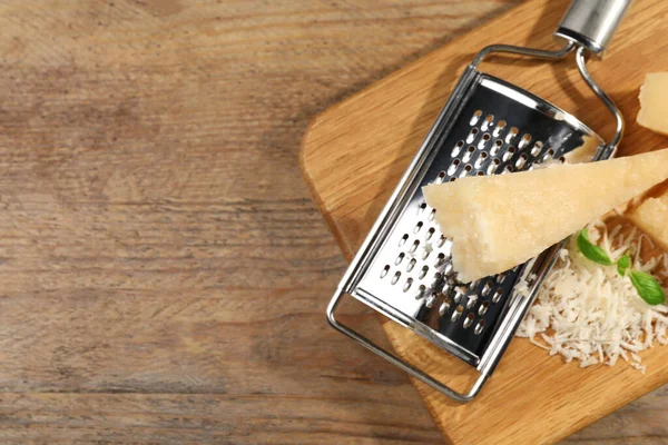 Parmesan cheese near grater on wooden table, top view. Space for text