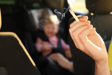 Anne arabada sigara ve çocukla, yakın plan. Çocukların yanında sigara içme.