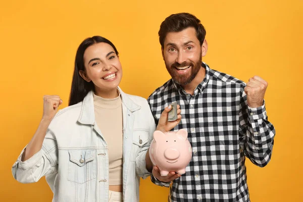 Pareja Feliz Con Alcancía Cerámica Dinero Sobre Fondo Naranja — Foto de Stock