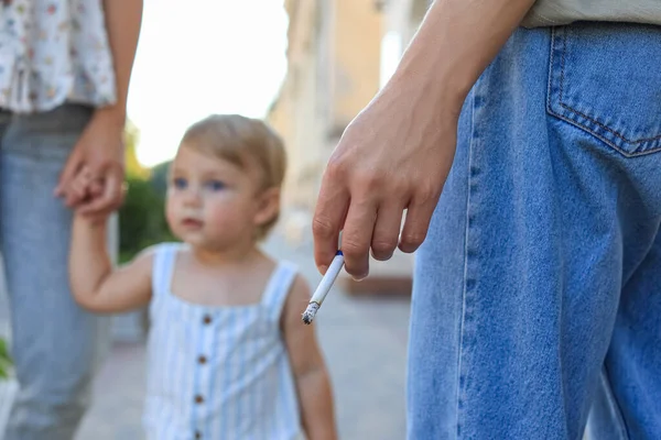 Woman smoking cigarette in public place outdoors, closeup. Don\'t smoke near kids