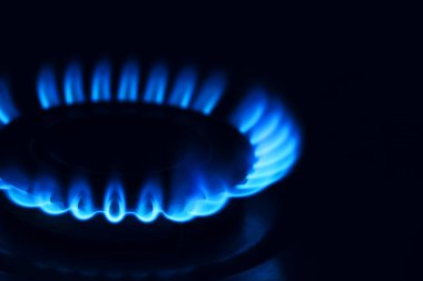 Karanlığın içinde yanan alevlerle gaz ocağı, yakın çekim