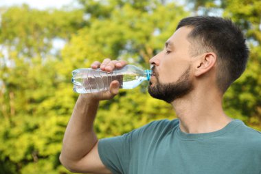 Man drinking water outdoors on hot summer day. Refreshing drink