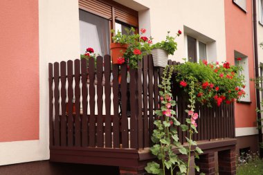 Wooden balcony decorated with beautiful red flowers