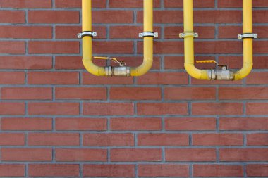 Kırmızı tuğla duvardaki sarı gaz boruları açık havada, metin için boşluk