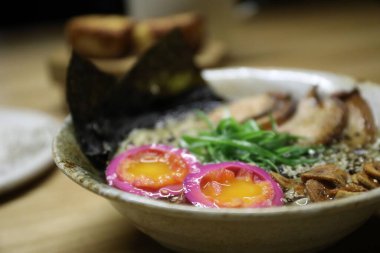 Bir kase ramen eriştesi, yumurta, salata ve susam tohumları, yakın plan.