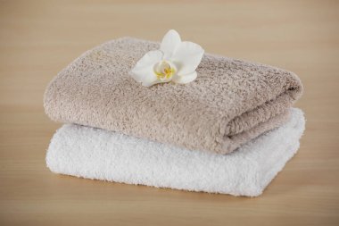 Soft folded towels with orchid flower on wooden table
