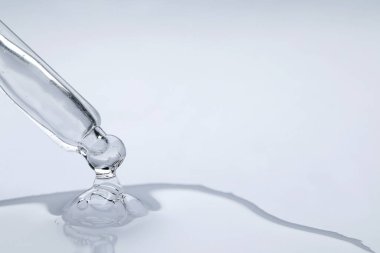 Beyaz arka planda pipetten damlayan yüz serumu, yakın plan. Metin için boşluk