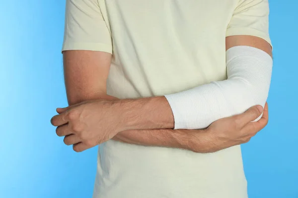 Hombre Con Brazo Envuelto Vendaje Médico Sobre Fondo Azul Claro —  Fotos de Stock