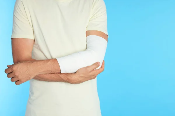 Mężczyzna Ręką Owiniętą Bandaż Medyczny Jasnoniebieskim Tle Zbliżenie Miejsce Tekst — Zdjęcie stockowe