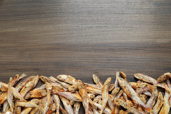 Tasty dried anchovies on wooden table, flat lay. Space for text