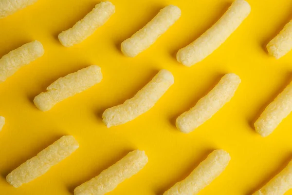 Tasty corn sticks on yellow background, flat lay