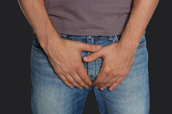 Man suffering from genital herpes on black background, closeup