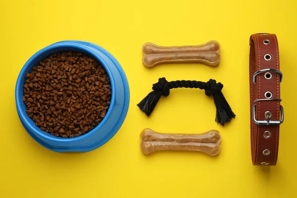Flat lay composition with pet toys and feeding bowl on yellow background