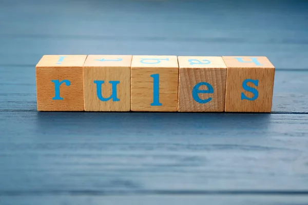 ライトブルーの木製のテーブルの上に文字でキューブで作られた言葉のルール — ストック写真