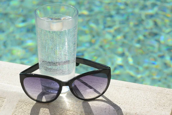 Κομψά Γυαλιά Ηλίου Και Ποτήρι Νερό Κοντά Εξωτερική Πισίνα Την — Φωτογραφία Αρχείου