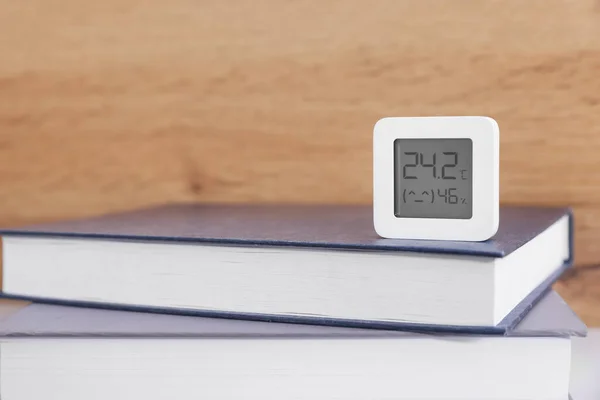 Digital hygrometer with thermometer on books. Space for text