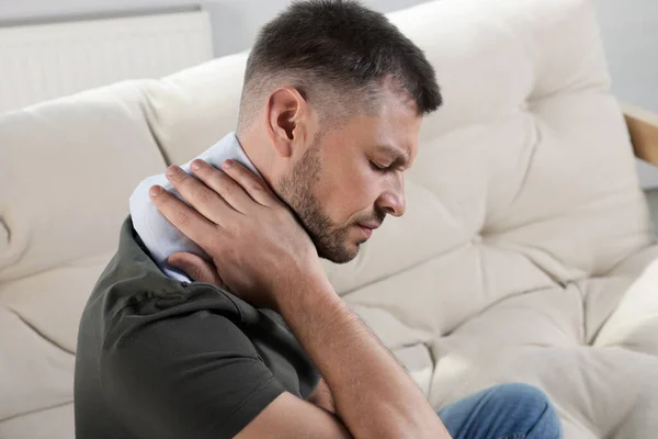 Uomo Utilizzando Pad Riscaldamento Sul Divano Casa — Foto Stock