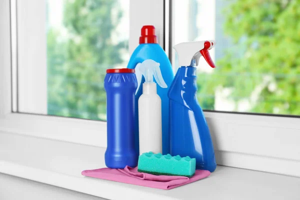 Different cleaning supplies and tools on window sill indoors