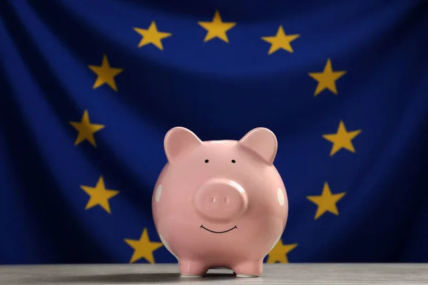 Pinkfarbenes Sparschwein Auf Hellgrauem Tisch Gegen Flagge Der Europäischen Union — Stockfoto