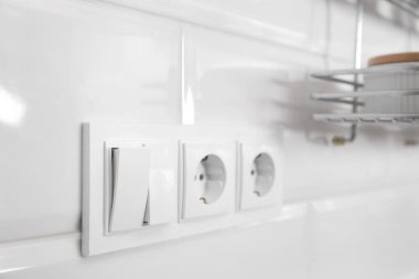 İçerideki beyaz duvarda elektrik düğmesi ve prizler var.