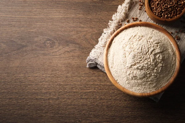 Buckwheat flour on wooden table, flat lay. Space for text