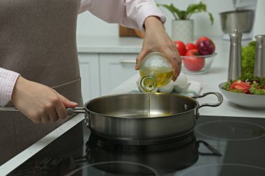 Kadın mutfaktan tavaya yağ döküyor, yakın plan.