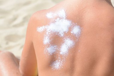 Sahilde güneş kremi sürmüş bir çocuk, yakın plan.