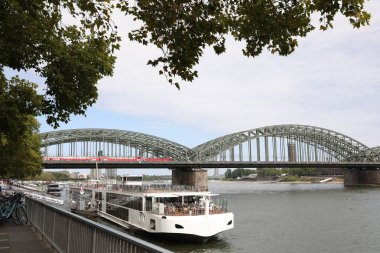 Köln, Almanya - 28 Ağustos 2022: Nehir ve feribot üzerinde modern bir köprü manzarası