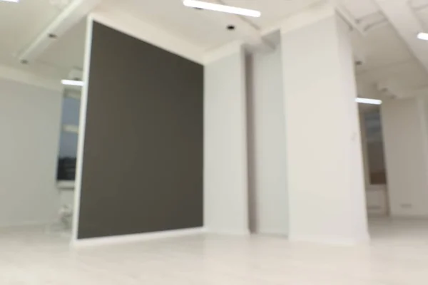 Blurred view of empty office room with color walls and modern lights on ceiling. Interior design
