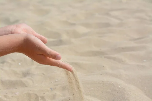 子供はビーチで手から砂を注ぎ テキストのためのスペースで閉じます 飛行時間の概念 — ストック写真