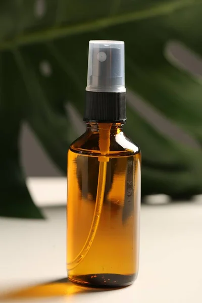 Rocíe Botella Con Aceite Hoja Verde Sobre Mesa Blanca Cosmética — Foto de Stock
