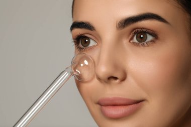 Woman using high frequency darsonval device on grey background, closeup
