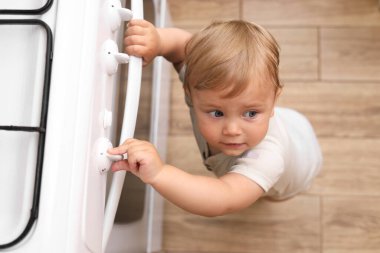 Küçük çocuk içeride gaz sobasıyla oynuyor, manzaranın üstünde. Mutfakta tehlikeler