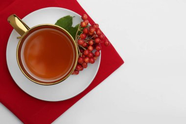 Bir fincan çay ve taze viburnum üzümleri beyaz masada, üst tarafta. Metin için boşluk