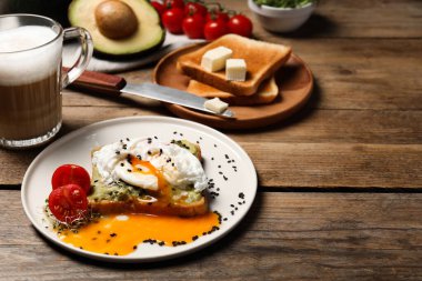 Ahşap masada servis edilen haşlanmış yumurta ve avokadoyla nefis bir tost.