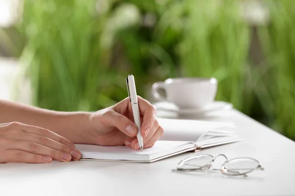 屋内の白いテーブルでノートに書く女性 クローズアップ — ストック写真