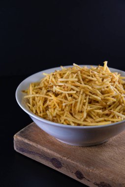 Beyaz kasede patates kızartması ve siyah arka plan.