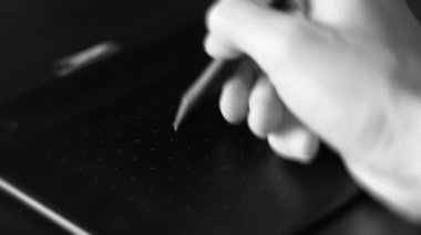 A hand draws with a stylus on a graphics tablet. Graphic designer and artist. creative work, inspiration and art. Electronic art equipment. Black and white closeup video