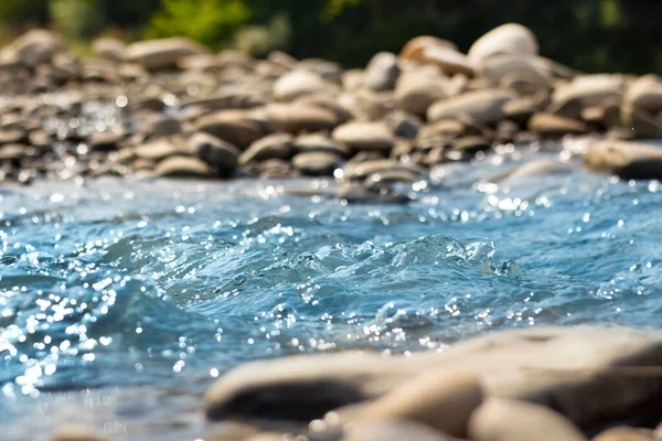 Rough current of a mountain river and stones. Beautiful movement of water in the wild. Freshness of nature. Wildlife photography for background