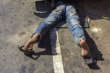 bir arabayı tamir ederken yere yatan adam