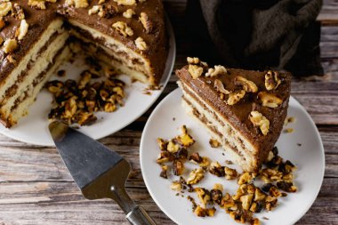 Ev yapımı çikolatalı pasta, kavrulmuş cevizli tatlı bisküvi, tatlı tatlı, ahşap arka planda kahverengi gıda rengi, yanında spatula ve ezilmiş ceviz.