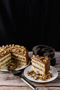 Ev yapımı çikolatalı pasta, kavrulmuş cevizli tatlı bisküvi, tatlı tatlı, ahşap arka planda kahverengi gıda rengi, yanında spatula ve ezilmiş ceviz.