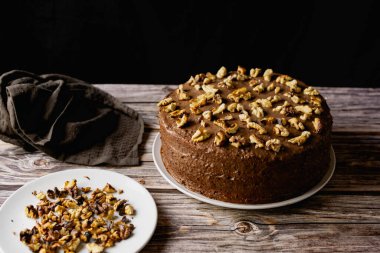 Ev yapımı çikolatalı pasta, kavrulmuş cevizli tatlı bisküvi, tatlı tatlı, ahşap arka planda kahverengi gıda rengi, yanında spatula ve ezilmiş ceviz.
